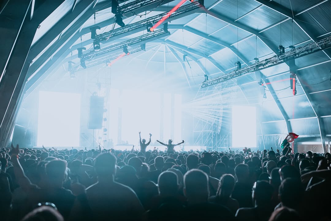 Carpa iluminada en blanco frío con el público con los brazos en alto